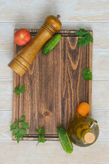 textured wooden cutting board and ingredients for cooking a summer salad with vegetables tomatoes cucumbers, parsley and herbs, olive oil and pepper mill, food background with copy space for text