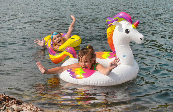 Happy Girl Relaxing In The Sea With Inflatable Ring Unicorn In Summer Time Vacation Outdoors