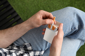 Man taking cigarette from pack outdoors, above view