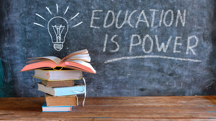 books and blackboard with drawing of a lightbulb and slogan education is...