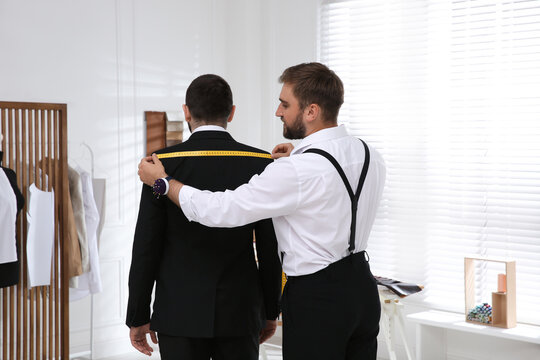 Professional tailor measuring client's shoulder width in atelier