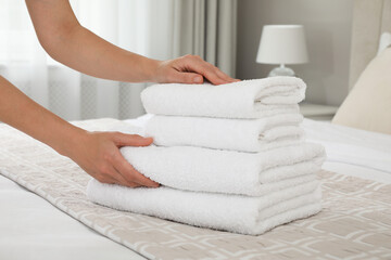 Obraz na płótnie Canvas Woman putting fresh towels on bed in room, closeup