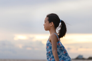 Portrait of little girl standing enjoy on the beach, Kid relaxing in summer sunset sky outdoor