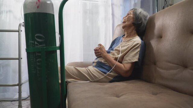 Elderly woman wearing oxygen nasal canula at home.
