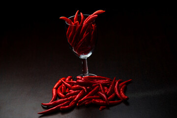 the exotic of the red chili peppers in glass cup with place on black background 