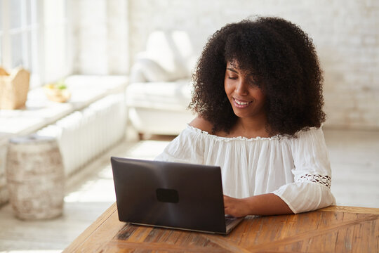 Focused young black woman student preparing for exams using laptop and sitting at table. Concentrated biracial female distant learning foreign languages and working distantly.