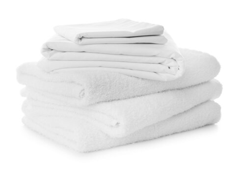 Stack of towels and bed sheets on white background