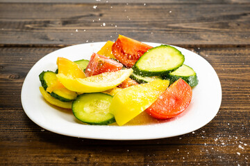 add salt and oil salad fresh vegetables cut into pieces on a white plate