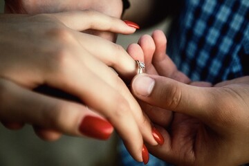 Obraz na płótnie Canvas Man putting on girl finger engagement ring close-up