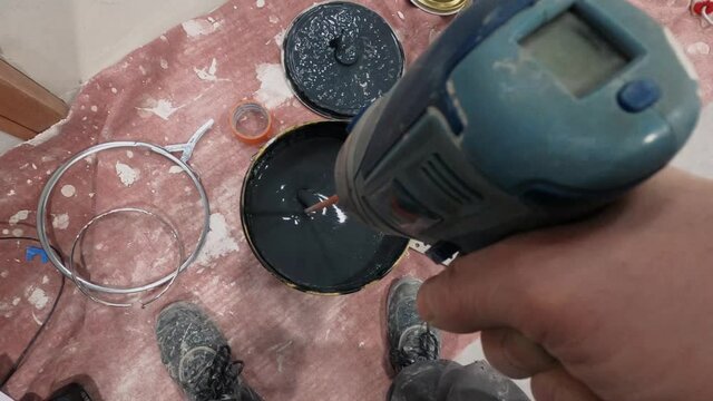 The Process Of Mixing paint and hardener in a Bucket with a driller