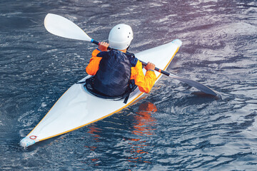 Young boy is engaged in water sports in a kayak or canoe and paddles on a pond during high water in...