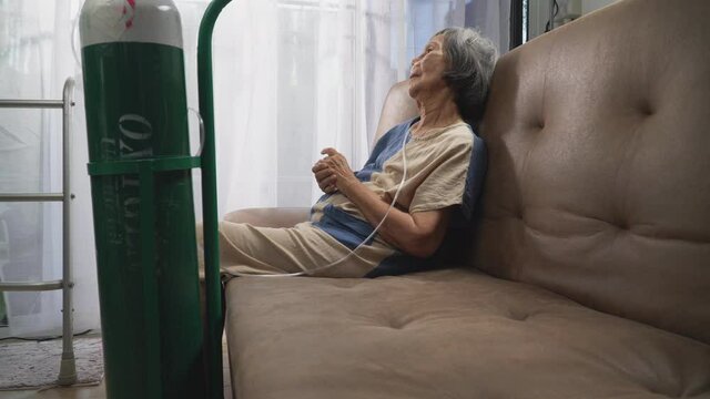 Elderly woman wearing oxygen nasal canula at home.