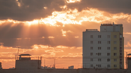 Dramatic sky through which the rays of the setting sun break through against the background of...