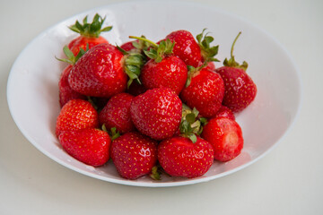 Harvest fresh ripe strawberries in a white plate on a white background. Close-up. Healthy eating. Vegetarian food.