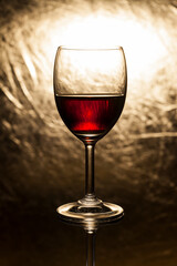 Red wine in glass on a gold background.