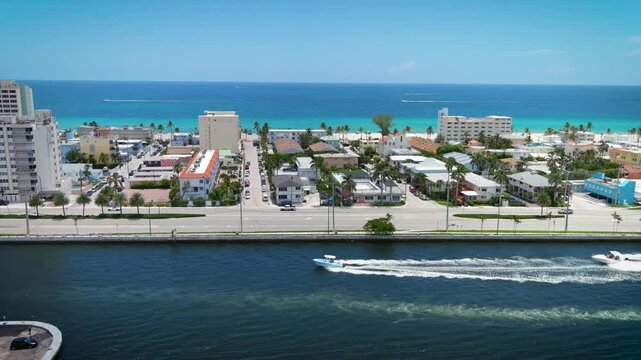 Aerial Flying Hollywood Intercoastal to Ocean East over water, land to ocean coastal barrier with buildings condos Resort