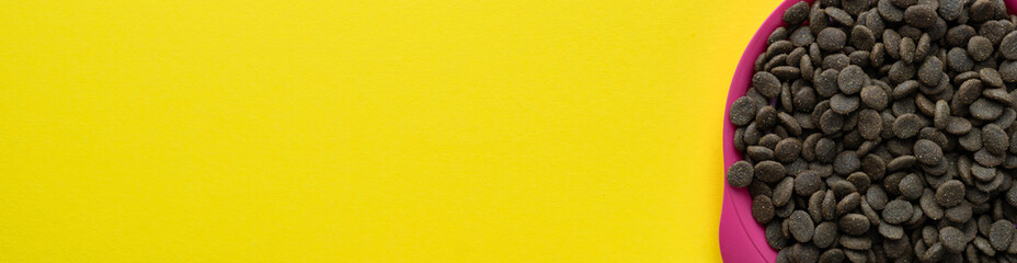 A bowl of dog food on a yellow background. Layout, banner, place for text. Flat lay.