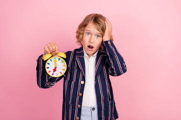 Photo of young school boy amazed shocked hand touch head oversleep late clock isolated over pink color background