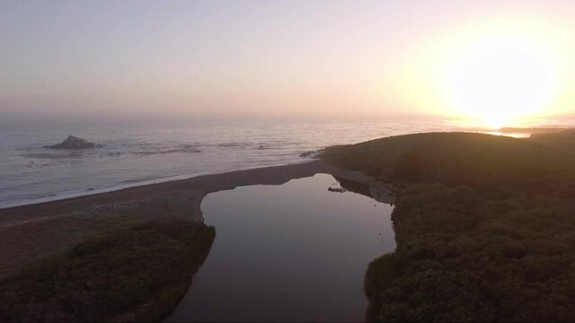 AERIAL - Creek ends just before ocean at sunset