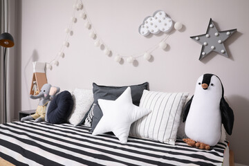 Comfortable bed with pillows and toys indoors. Cute kids room interior