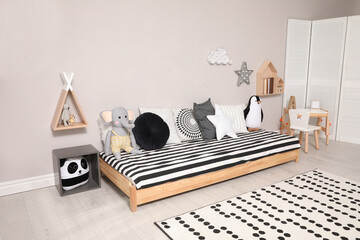 Cute kids room with stylish comfortable floor bed and toys. Montessori interior