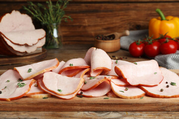 Delicious sliced ham with thyme and peppercorns on wooden table