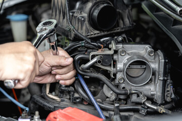 Close up wrench in hand a man  remove bolt of engine in car service engine throttle valve cleaning and maintenance : car service concept photo