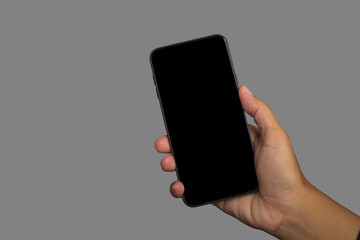 Hand holding of a smartphone with a gray background. Close-up photo. Space for text. Technology and communication concept