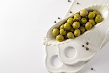 green olives in decorative dishes on white background, top view, empty space for text