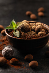 natural chocolate truffles with mint in decorative dishes, close-up, dark background, gloomy mood