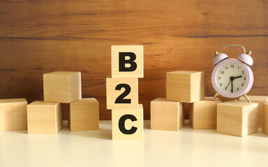Three wooden cubes stacked vertically on a brown background make up the word B2C.