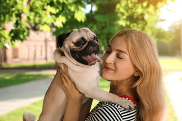 Woman with cute pug dog outdoors on sunny day. Animal adoption