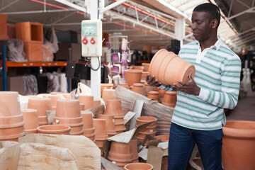 Portrait of African American man choosing pots for flowers and trees in gardening market