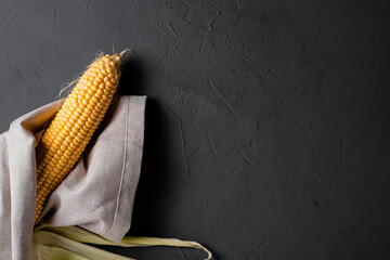 Peeled raw corn on a gray concrete background.