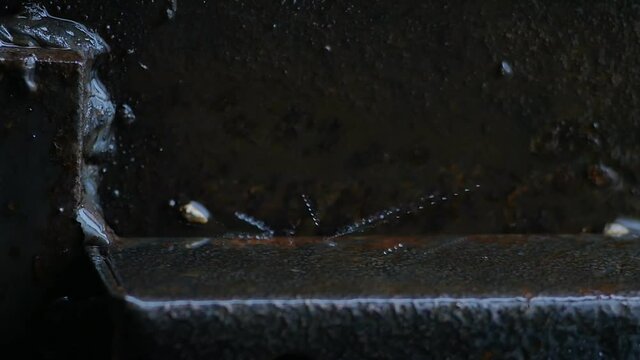 drops of water from heavy rain fall on metal surfaces in a dark place. Metal lines are parallel and perpendicular. Textured and embossed surfaces. Close-up