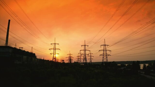 Electricity pylons at sunset. Transmission towers. Silhouette of high-voltage electic towers that transport electric power from generating stations to electrical substations. Aerial view.
