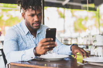 Young man using his mobile phone at a restaurant.