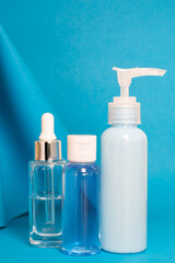 Art colourful geometry blue style and skin care cosmetics. Origami in a blue colour and cosmetics in white and blue colours: serum, face cream, face tonic. Paper mock up and luxury cosmetic. 