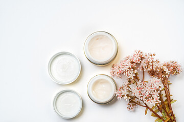 cosmetics for the face. eye cream and a bunch of pink flowers on a white background