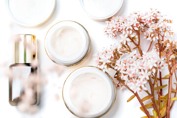 cosmetics for the face. eye cream and a bunch of pink flowers on a white background