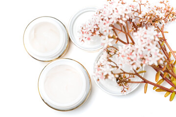 cosmetics for the face. eye cream and a bunch of pink flowers on a white background