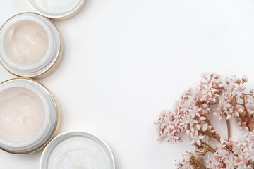 cosmetics for the face. eye cream and a bunch of pink flowers on a white background