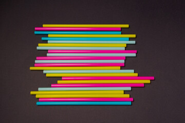 Fototapeta premium colourful cocktails straw for drinks in pink, yellow, blue colours on a dark background 