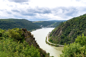 Fototapeta na wymiar The river Rhine in western Germany flows between the hills covered with forest, visible river bend and rock cliff.