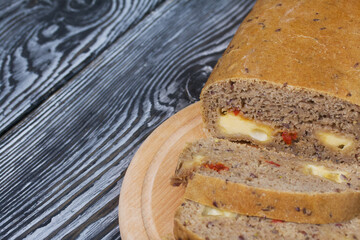 Homemade bread with tomatoes and cheese. Several slices are cut. They lie next to the loaf.