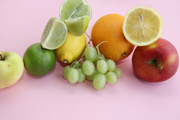 Fototapeta na wymiar fresh fruit apple, lime, avocado, lemon, orange, grapes on a light pink background