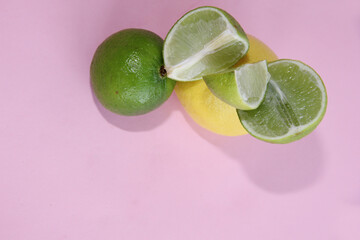 lime and lemon on a pink background.lime slices and lemon in the cut