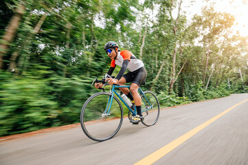 A man ride on bike on the road. Man riding vintage sports bike for evening exercise. A man ride bicycle to breathe in the fresh air in midst of nature, meadow, forest, with evening sun shining through