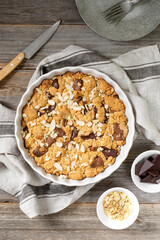 Homemade shortbread pie with milk and bitter chocolate in a baking dish on a gray wooden culinary background top view. Delicious rustic sweet pastries	