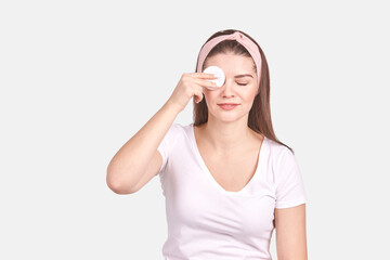 Fototapeta premium Pretty young woman gesture. Studio portrait. Female person. Isolated background. Morning bathroom routine. round cotton pad. Facial clean concept. Remove makeup lotion